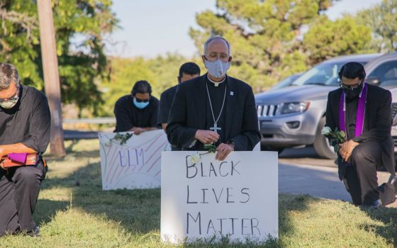 Bishop Mark Seitz of El Paso, Texas, kneels at El Paso's Memorial Park holding a Black Lives Matter sign June 1. (CNS/Courtesy of El Paso Diocese/Fernie Ceniceros)