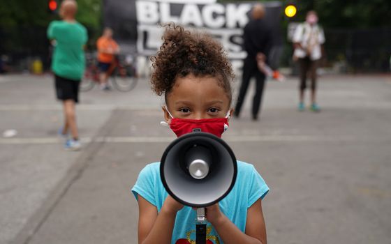 Mischa, 6, from Maryland, holds a bullhorn in front of a "Black Lives Matter" protest sign near the White House June 10, 2020, in Washington. (CNS/Kevin Lamarque, Reuters)