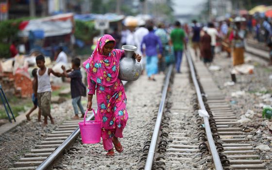 A woman carries drinking water along railroad tracks Sept. 15 in a poor section of Dhaka, Bangladesh. (CNS/Mohammad Ponir Hossain, Reuters)