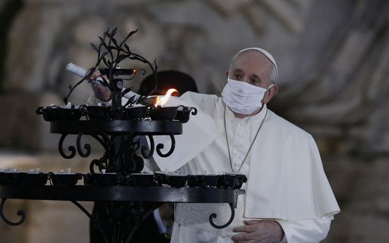 Pope Francis lights a candelabra at the conclusion of an encounter to pray for peace in Piazza del Campidoglio in Rome Oct. 20. (CNS/Paul Haring)