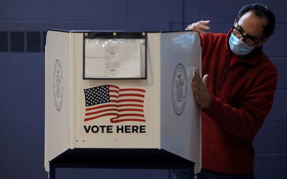 A man sanitizes a voting booth to fight the spread of the coronavirus disease at a polling station Oct. 25 on Staten Island, New York. (CNS/Reuters/Andrew Kelly)