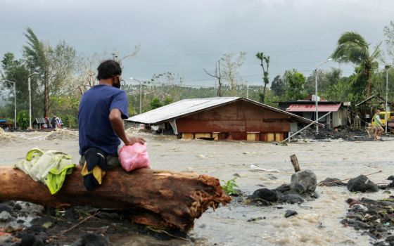 A man looks at his house buried under the pile of rubble and sand in Daraga, Philippines, Nov. 1, following flash floods brought by Super Typhoon Goni, also known as Rolly. The storm left at least 10 people dead and three missing. (CNS/Reuters)