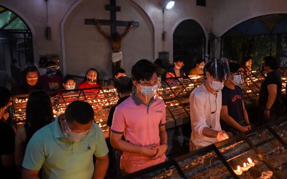 People wearing protective masks and face shields light candles after the first of the nine-day novena Masses for Simbang Gabi at the National Shrine of Our Mother of Perpetual Help in Manila, Philippines, Dec. 16, 2020. (CNS/Reuters/Lisa Marie David)