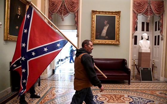 A supporter of President Donald Trump carries a Confederate battle flag on the second floor of the U.S. Capitol building in Washington near the entrance to the Senate after breaching security defenses Jan. 6. (CNS/Reuters/Mike Theiler)