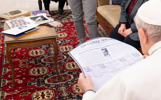 Pope Francis looks at a copy of the April 11, 1920, edition of the "Catholic News Sheet," during a meeting with members of the Catholic News Service Rome bureau at the Vatican Feb. 1, 2021.