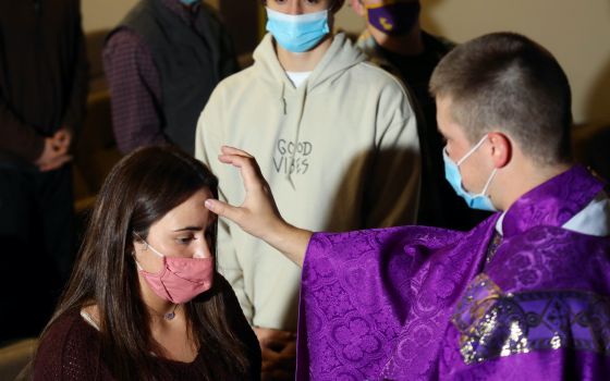 Father Andy Hammeke, associate pastor of St. Mary, Queen of the Universe in Salina, Kans., places ashes on Kansas Wesleyan University students during Ash Wednesday Mass in Fitzpatrick Auditorium Feb. 17, 2021, amid the coronavirus pandemic. 