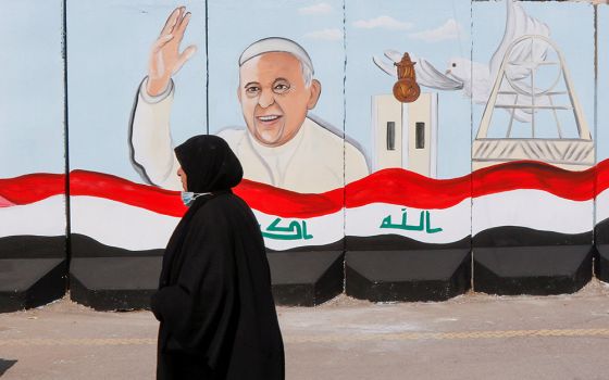 A woman walks past a mural of Pope Francis on a wall surrounding a church in Baghdad Feb. 22. (CNS/Reuters/Khalid al-Mousily)