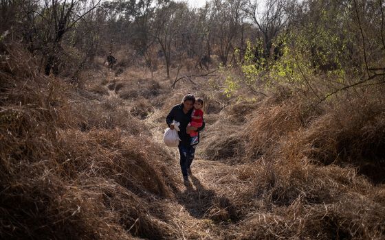 A Honduran migrant carries her baby into Penitas, Texas, after crossing the Rio Grande River from Mexico March 10. (CNS/Adrees Latif, Reuters)