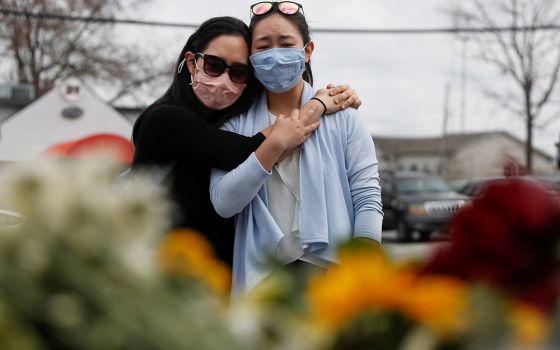 Women in Atlanta embrace March 19, after laying flowers at a makeshift memorial outside the Gold Spa following the deadly shootings March 16 at three day spas in metro Atlanta. Commentator Clarissa V. Aljentera received texts from friends and family, rela