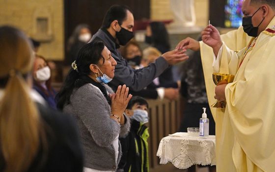 A woman receives Communion during a memorial Mass for Fr. Jorge Ortiz-Garay at St. Brigid Church in Brooklyn, New York, March 27, on the first anniversary of the priest's death from COVID-19.