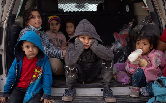 Migrant children from Central America take refuge from the rain in the back of a U.S. Border Patrol vehicle in Penitas, Texas, March 14, as they await to be transported after crossing the Rio Grande into the United States. (CNS/Reuters/Adrees Latif)