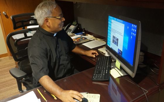 Father Aby Abraham, associate pastor at the Cathedral of St. Andrew in Little Rock, Ark., reads an India Times article about the ongoing COVID-19 crisis in India May 5, 2021. (CNS photo/Aprille Hanson Spivey, Arkansas Catholic)
