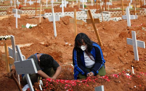 Indah Wulandari, 35, and her son, Nicolas Tegar, 12, pray July 15 at the grave of her husband at a government cemetery for COVID-19 victims in Bekasi, Indonesia. (CNS/Reuters/Willy Kurniawan)