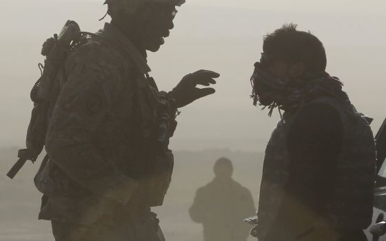 U.S. soldier Sgt. Michael Webb, left, from 549th MP Company Task Force Bronco and a translator are silhouetted as they talk to each other at a joint U.S. military and Afghan police checkpoint in Nangarhar province in eastern Afghanistan March 7, 2012. (CN