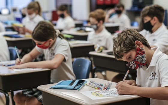 Students work at their desks on the first day of the new school year at St. Matthew School in Franklin, Tenn., Aug. 6, 2020, with extensive COVID-19 protocols in place, including temperature screening and mandatory face masks for each student. In Louisian
