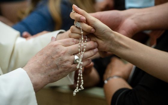 Pope Francis greets a person with a rosary during his general audience in the Vatican's Paul VI hall Aug. 18, 2021. The pope continued his series of talks on St. Paul's Letter to the Galatians. The pope said the law was meant to teach the path toward true