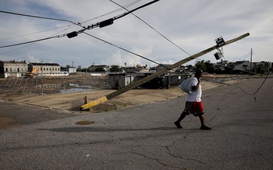 A man in New Orleans walks past a damaged electric line Aug. 30, after Hurricane Ida made landfall. (CNS photo/Marco Bello, Reuters)