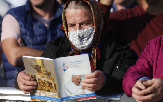 A woman holds the Mass program as she waits for Pope Francis' arrival to celebrate Mass on the plains of the Basilica of Our Lady of Seven Sorrows in Šaštin, Slovakia, Sept. 15, 2021. (CNS photo/Paul Haring)