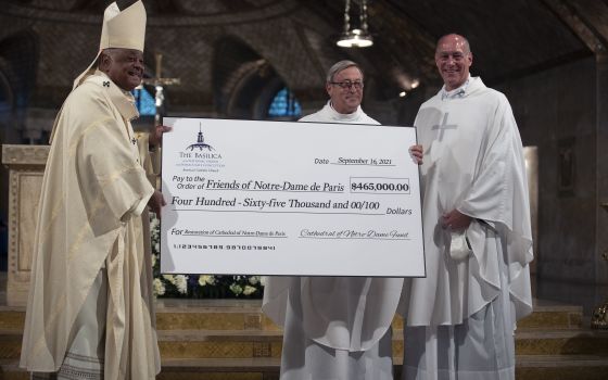 Msgr. Patrick Chauvet, center, rector of the Notre Dame Cathedral in Paris, receives a check from Msgr. Walter Rossi, rector of the Basilica of the National Shrine of the Immaculate Conception in Washington, and Washington Cardinal Wilton D. Gregory after