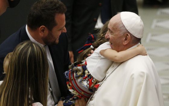 A young girl embraces Pope Francis during his general audience in the Paul VI hall at the Vatican Sept. 22, 2021. (CNS photo/Paul Haring)