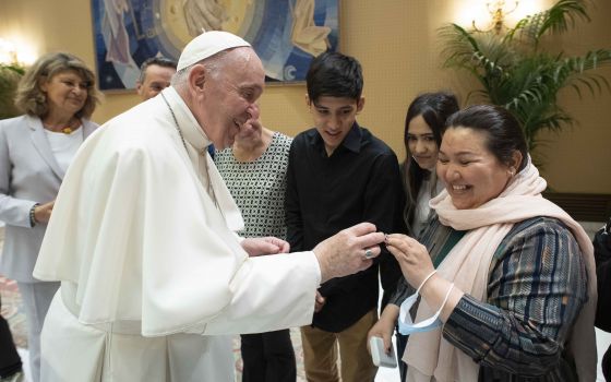 Pope Francis accepts a wedding ring from a woman whose husband was killed by the Taliban, during a meeting with families from Afghanistan prior to his general audience in the Paul VI hall at the Vatican Sept. 22, 2021. The pope met three Christian familie