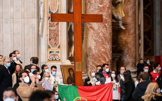 Young people from Portugal are pictured with the World Youth Day cross and their country's national flag following the cross' handover from their Panamanian peers at the end of Pope Francis' Mass Nov. 22, 2020. (CNS photo/Vincenzo Pinto, Reuters pool)
