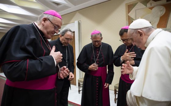 Pope Francis and four French bishops make the sign of the cross during silent prayer for the victims of abuses committed by members of the clergy, prior to the pope's general audience at the Vatican Oct. 6, 2021. The bishops were visiting Rome following a