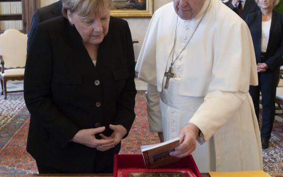 Pope Francis and German Chancellor Angela Merkel exchange gifts during a private meeting at the Vatican Oct. 7, 2021. (CNS photo/Vatican Media)