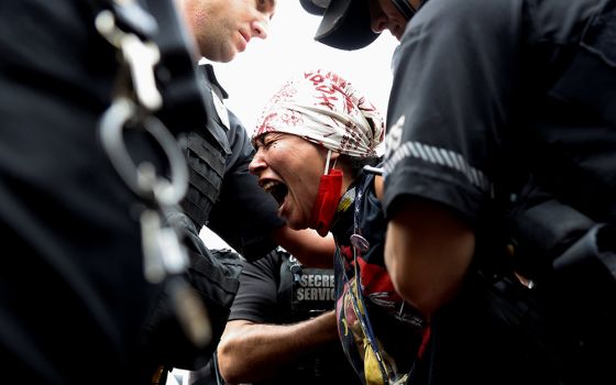 A demonstrator near the White House in Washington is arrested by U.S. Secret Service agents Oct. 11, during a climate change protest to mark Indigenous Peoples Day. (CNS/Reuters/Evelyn Hockstein)