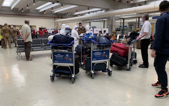 Barnabite Father Giovanni Scalese holds a baggage trolley, right, as he arrives with five Missionaries of Charity nuns at Rome's Fiumicino airport Aug. 25, 2021, after the group was evacuated from Afghanistan. Father Scalese, who was head of the sole Cath