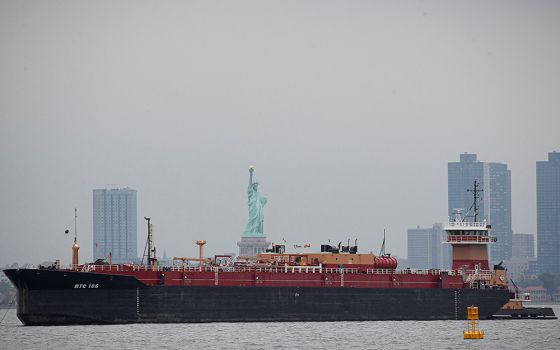A tugboat in New York City pushes a fuel oil barge past the Statue of Liberty Oct 13, 2021. (CNS/Reuters/Brendan McDermid)