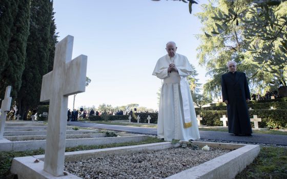 Pope Francis prays at a grave at the French Military Cemetery before celebrating Mass for the feast of All Souls at the cemetery in Rome Nov. 2, 2021. (CNS photo/Vatican Media)