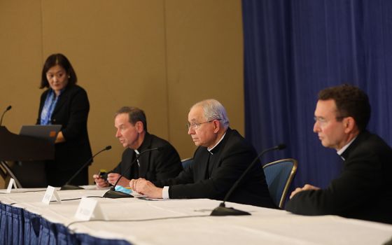 Bishop Michael Burbidge, Archbishop José Gomez , president of the U.S. bishops' conference, and Auxiliary Bishop Andrew Cozzens attend a Nov. 16 news conference during the bishops' fall assembly in Baltimore. At the podium is Chieko Noguchi. (CNS)