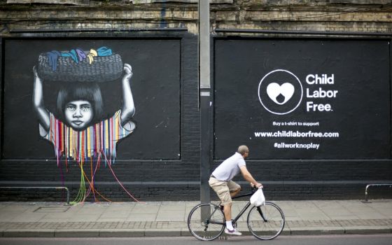 A cyclist passes a mural created by street artists depicting child labor in London June 8, 2016. (CNS photo/Shanshan Chen, Reuters)