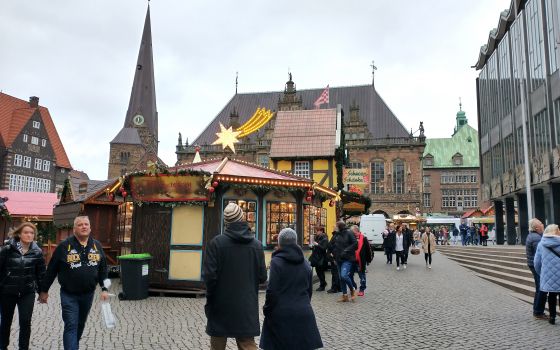 People walk through the Christmas market on the square in front of the historic Town Hall in the northern German city of Bremen before it opened Nov. 22, 2021. (CNS photo/Anli Serfontein)