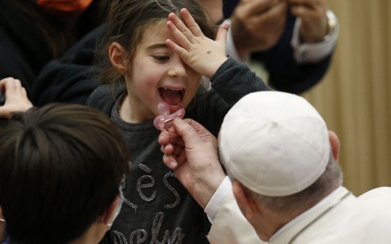 Pope Francis puts a pacifier into a child's mouth during his general audience in the Paul VI hall at the Vatican Nov. 24, 2021. (CNS photo/Paul Haring)