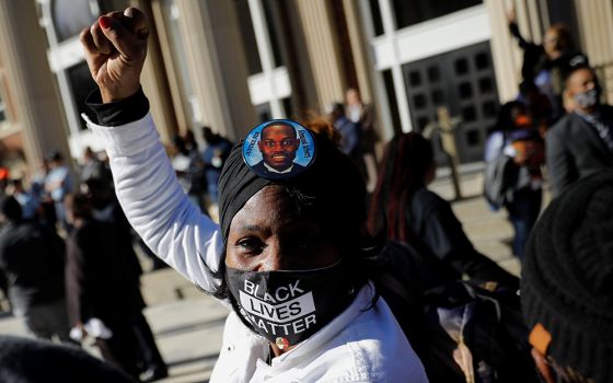 A woman outside the Glynn County Courthouse in Brunswick, Georgia, raises her fist Nov. 24, after the jury reached a guilty verdict in the trial of the men convicted of the February 2020 murder of 25-year-old Ahmaud Arbery. (CNS/Reuters/Marco Bello)