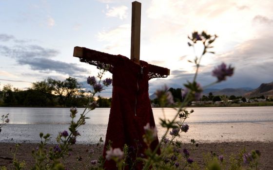 A child's red dress hangs on a stake near the grounds of the former Kamloops Indian Residential School in Kamloops, British Columbia. For years, Indigenous people in Canada have wanted an apology from the pope — on Canadian soil — for the church's role in