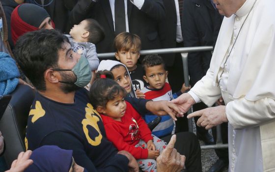 Pope Francis holds the hand of a man during a visit with refugees at the government-run Reception and Identification Center in Mytilene, Greece, Dec. 5, 2021. (CNS photo/Paul Haring)