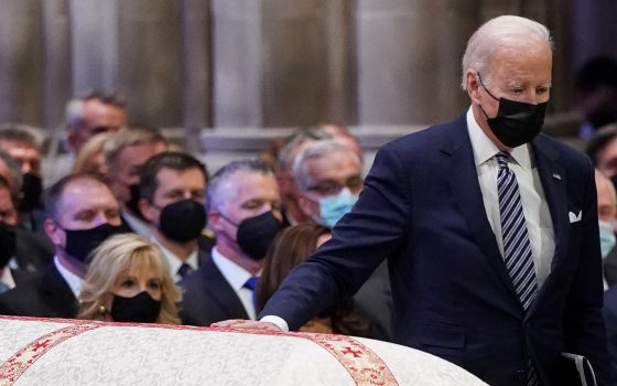 President Joe Biden touches the casket of the late Senate Majority Leader Bob Dole, R-Kan., at the National Cathedral in Washington as he walks up to speak during a Dec. 10, 2021, funeral service. (CNS photo/Kevin Lamarque, Reuters)