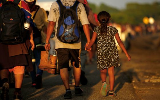 Jose Francisco from Honduras leads his 8-year-old daughter, Zuabelin, by the hand Nov. 22, 2021, as they took part in a caravan near Villa Mapastepec, Mexico, and headed to the U.S. border. (CNS photo/Jose Luis Gonzalez, Reuters)