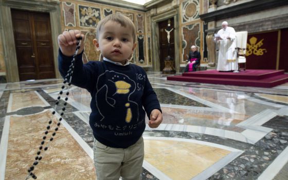 Pope Francis speaks as a boy holds a rosary during a meeting with children from Italy's Catholic Action at the Vatican Dec. 18, 2021. (CNS photo/Vatican Media)