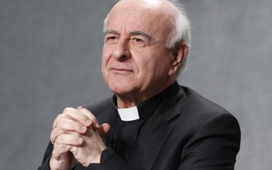 Archbishop Vincenzo Paglia, an older white man, folds his hands and stares off camera