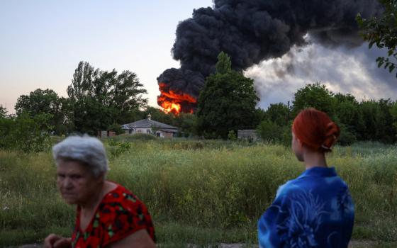 Local residents in Donetsk, Ukraine, look on as smoke rises after shelling from Russia July 7, 2022. (CNS photo/Alexander Ermochenko, Reuters)