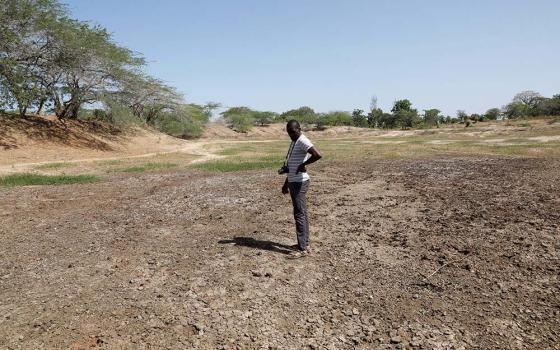 Scientist Chris Shitote examines a dry water hole in Kilifi, Kenya, Feb. 16. In recent years, nations have been quick to make pledges to confront climate change. Pledges, alas, need to be implemented and that has proven more difficult. (CNS/Reuters/Baz Ratner)
