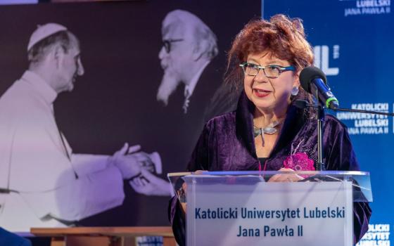 An older white, red-haired woman stands at a podium with the words Katolicki Uniwersytet Lubelski Jana Pawla II
