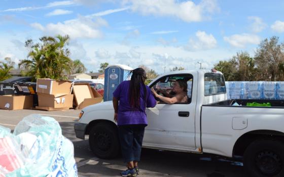 Lizvelle Rivera sits in a pickup truck and thanks a Catholic Charities Diocese of Venice volunteer for the supplies she received Oct. 10, 2022.