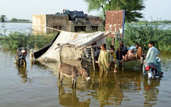 People wade in floodwaters outside their home, following heavy rains during the monsoon season in Sohbatpur district of Pakistan, Aug. 28, 2022. 