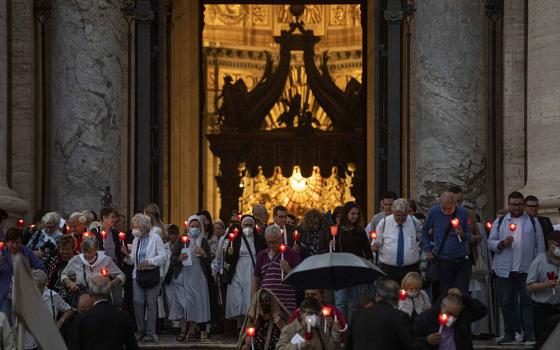 People holding lighted candles leave St. Peter's Basilica after Pope Francis celebrated Mass Oct. 11 to mark the 60th anniversary of the opening of the Second Vatican Council. (CNS/Vatican Media)