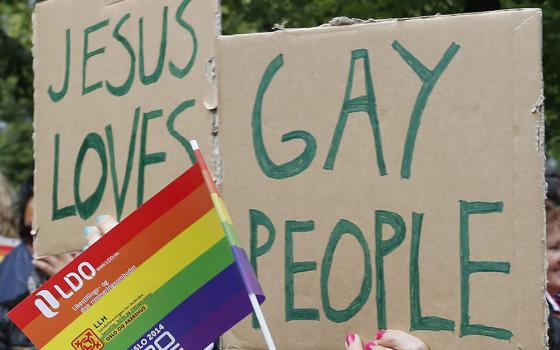 People hold a rainbow flag and signs during a 2014 gay pride parade in Oslo, Norway. In Zambia, some LGBTQ+ Catholics said a church campaign against homosexuality has made them feel unsafe. (CNS/Terje Bendiksby, NTB Scanpix via Reuters)